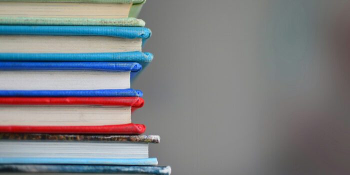 Pile of books each with different colour covers in focus with blurred background